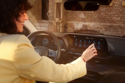 Vrouw gebruikt de 10,25-inch touchscreen in de Hyundai BAYON, de nieuwe, compacte crossover-SUV.
