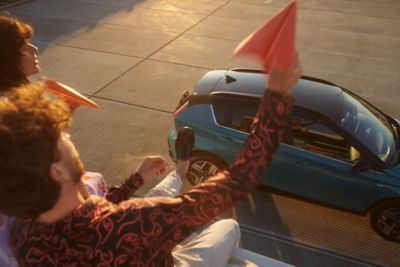 Two people throwing paper planes over the Hyundai BAYON compact crossover SUV