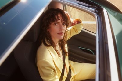 Kobieta patrząca przez okno dachowe w samochodzie Hyundai BAYON.