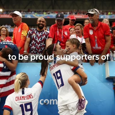 Fußballfans auf einer Tribüne, im Vordergrund eine Frau mit einem kleinen Mädchen auf dem Arm - Schriftzug “to be proud supporters of”.