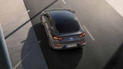 Dach i tył nowego Hyundaia i30 Fastback w kolorze Shadow Grey – ujęcie z góry na drodze.