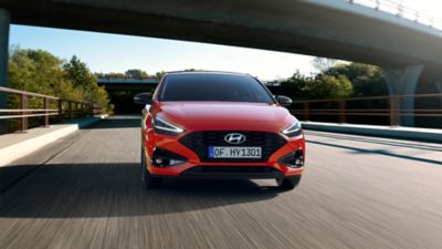 Kvinna och Hyundai i30 mildhybrid i stadsmiljö.