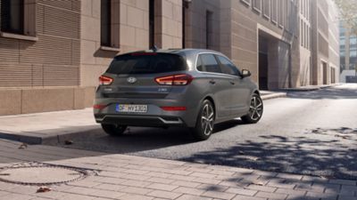Rear three-quarters view of the new Hyundai i30 in grey, parked in a city street.