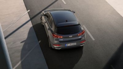 The Hyundai i20 in Lucid Lime Metallic parked in front of a shop.