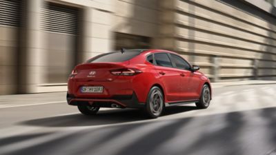 Hyundai i30 Fastback N Line jadący ulicą miasta – widok z tyłu.