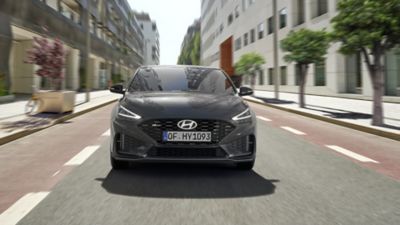 Mężczyzna biegnący na tle Hyundaia i30 Fastback.