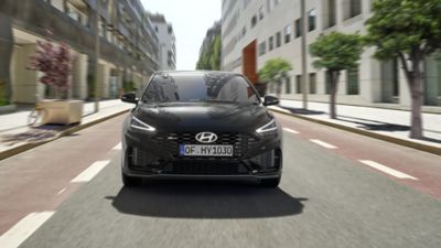Ein Hyundai i30 N Line, von vorne gesehen, fährt auf einer baumbestandenen Innenstadtstraße.