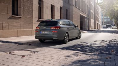 Rear three-quarters view of the new Hyundai i30 Wagon in grey, in a city street.