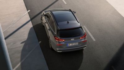 El techo y la parte trasera del nuevo Hyundai i30 CW en color gris, vistos desde arriba en una carretera.