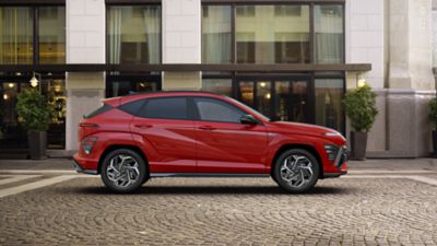 The KONA N Line in red parked next to a modern building.
