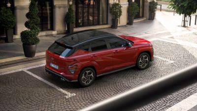 Ein vor einem Hotel parkender Hyundai KONA N Line mit Glas-Schiebedach in der Draufsicht.