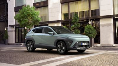 The all-new Hyundai KONA is pictured from the side driving down a city street.