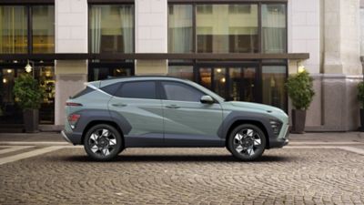 De man die de deur van de geheel nieuwe Hyundai KONA in het groen opendeed, parkeerde voor een gebouw.