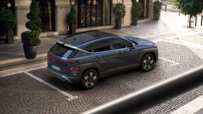 Ein blauer Hyundai KONA parkt vor einem innerstädtischen Gebäude.