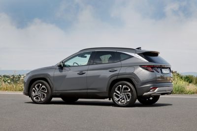 Zijaanzicht stilstaande Hyundai TUCSON op een weg langs een duingebied.