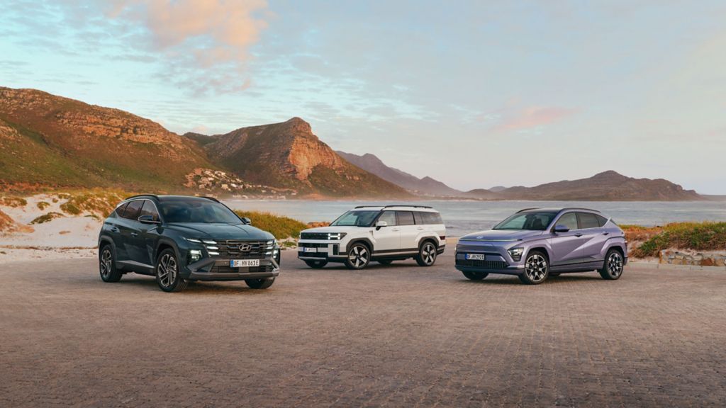 Tre Hyundai-bilar parkerade i ett öppet landskap med berg i bakgrunden.
