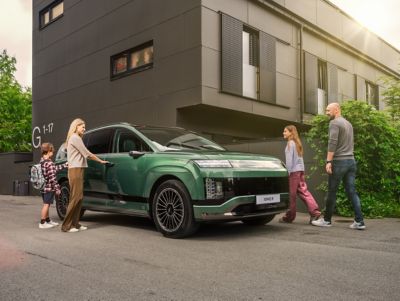 Hyundai IONIQ 9 schuin vooraanzicht met gezin bij woning