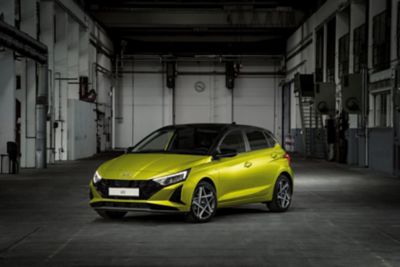 The new Hyundai i20 in yellow parked in a chic industrial setting.