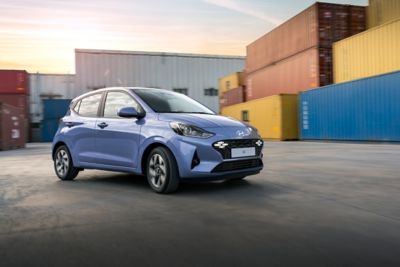 The Hyundai i10 driving next to colourful shipping containers.