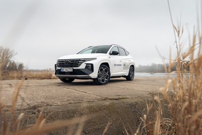 Hyundai TUCSON Plug-in Hybrid zaparkowany między trawami nad brzegiem rzeki