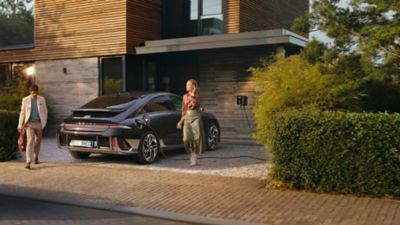 Hyundai IONIQ 6 in carica con ragazza che cammina accanto 