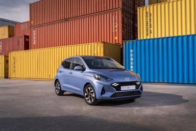 Nuevo Hyundai i10 aparcado junto a contenedores de carga de varios colores.