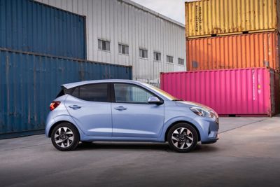 The new Hyundai i10 shown in profile next to colourful shipping containers.
