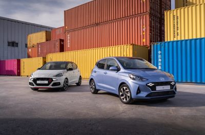 Ein Hyundai i10 und ein Hyundai i10 N Line, schräg von vorne aufgenommen, vor Industriecontainern.