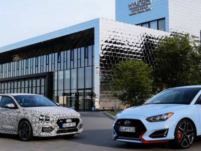 Een Hyundai i20 N en i30 Fastback N geparkeerd voor het Europees technisch centrum van Hyundai op de Nürburgring Nordschleife.
