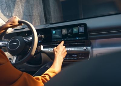 A man pressing the centre touch screen in the Hyundai KONA.