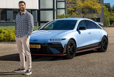 De Nederlandse content creator Amrit Hoeba staand voor de neus van een Hyundai IONIQ 6 N.