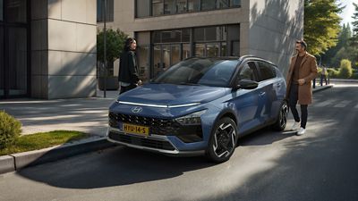 Een vrouw loopt weg van een geparkeerde Hyundai BAYON, de nieuwe, compacte crossover-SUV.