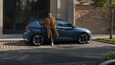 Hyundai BAYON parked at a sidewalk in a city.