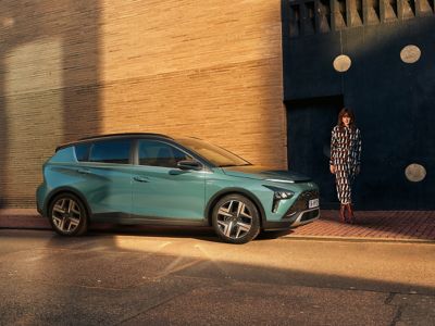 Hyundai BAYON Mild Hybrid parcheggiata con accanto una donna