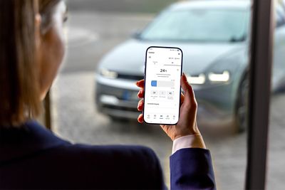 A hand holding a mobile phone showing the IONIQ 5 on the Bluelink app.