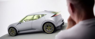 Person observing the Hyundai Concept THREE from the side in a studio setting.