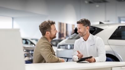 Customer receiving Hyundai vehicle advice and purchase support in a Hyundai dealership showroom.