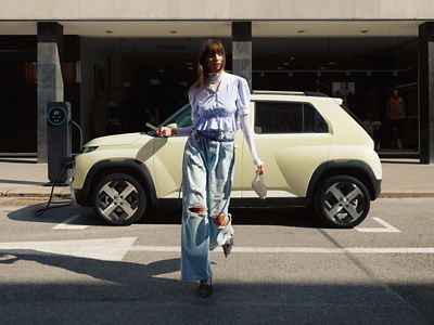 Een vrouw loopt weg van de nieuwe Hyundai INSTER, een elektrische auto die langs de straat geparkeerd staat.
