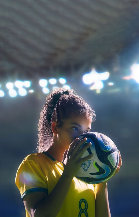 jugadora de fútbol besando el balón en un estadio