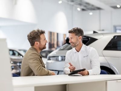 Customer receiving Hyundai vehicle advice and purchase support in a Hyundai dealership showroom.