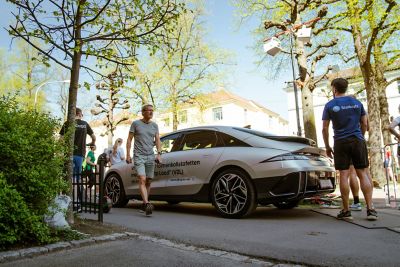 Flere folk passerer en parkert IONIQ 6 foliert med info om Holmenkollstafetten. Foto.