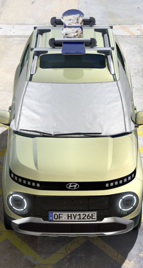 A woman walking away from the new Hyundai INSTER small electric car parked side of the street.