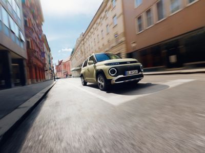  The new Hyundai INSTER small electric car driving down a city street.