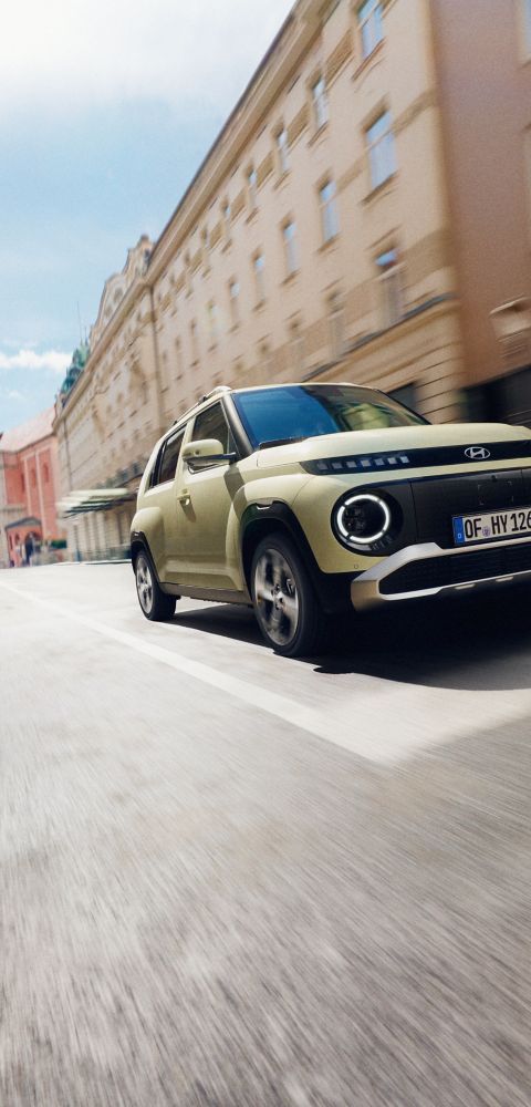 The Hyundai INSTER small electric car driving down a city street.