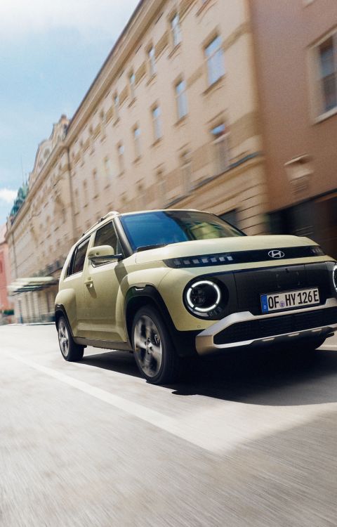 El Hyundai INSTER, coche eléctrico urbano, circulando por una calle de la ciudad.