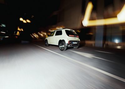 A rear view of the new Hyundai INSTER small electric car driving on the street.