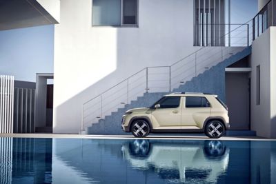 Driekwart vooraanzicht compacte elektrische auto Hyundai INSTER, rijdend in een bocht in de stad.