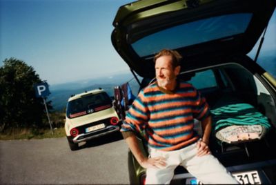 A man sitting in the opnend trunk of the new Hyundai INSTER small electric car. 