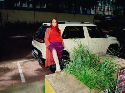 A woman leaning onto the new Hyundai INSTER small electric car.