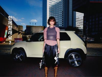 A woman standing in front of the new Hyundai INSTER small electric car.